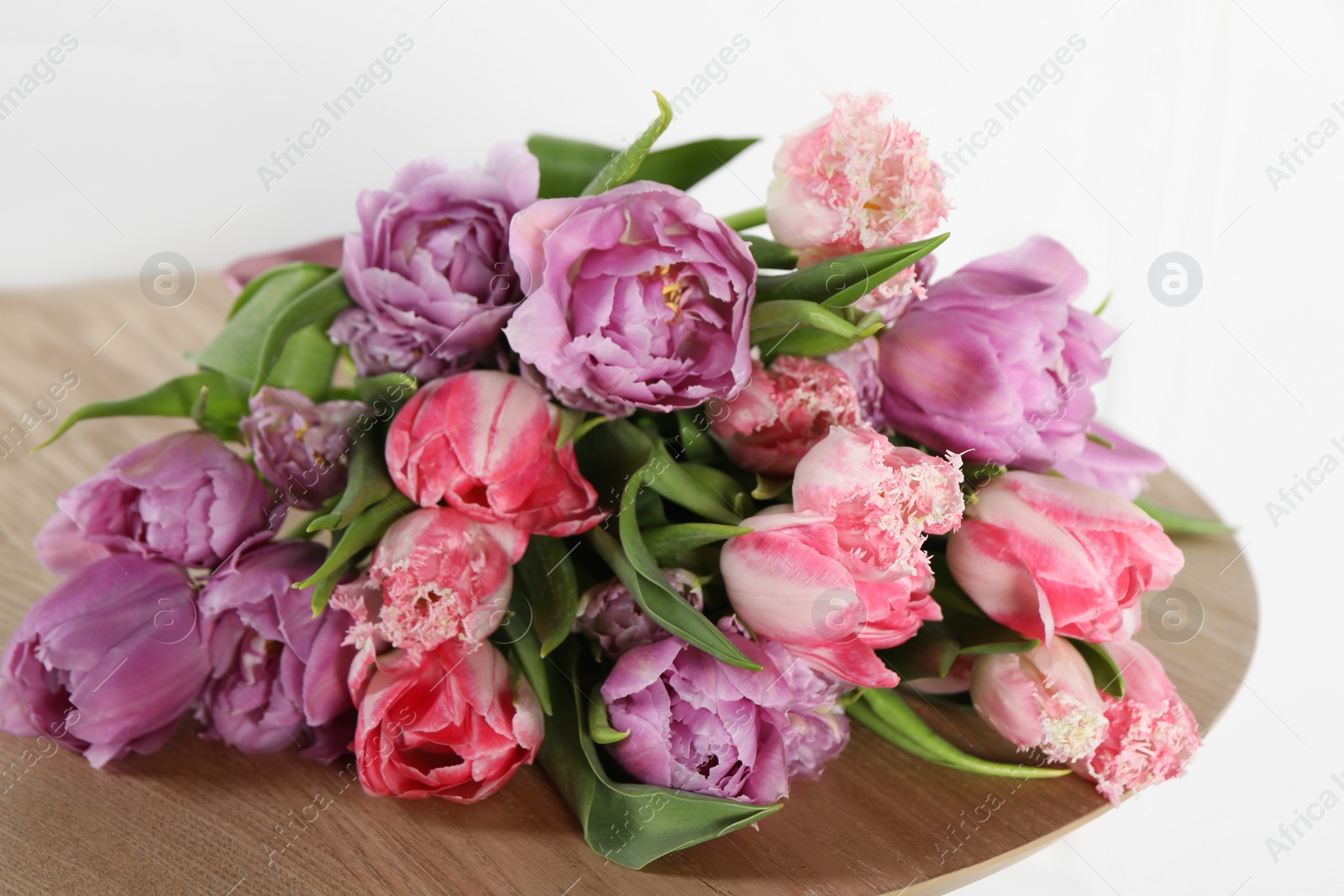 Photo of Beautiful bouquet of colorful tulip flowers on wooden table