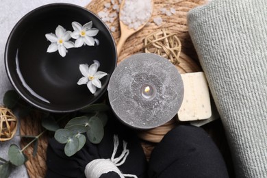 Flat lay composition with herbal massage bags, spa products and flowers on light grey table