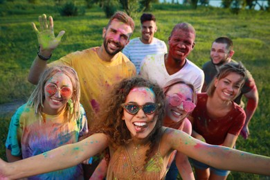 Photo of Happy friends covered with colorful powder dyes outdoors. Holi festival celebration
