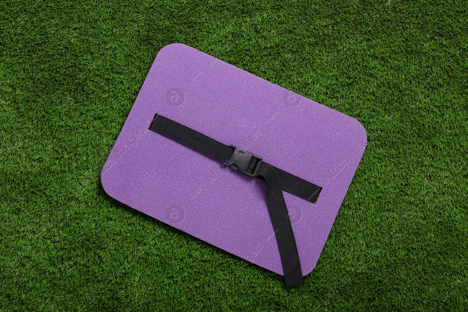 Photo of Violet foam seat mat for tourist on green grass, top view