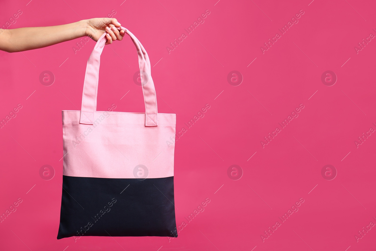 Photo of Young woman holding textile bag on pink background, closeup