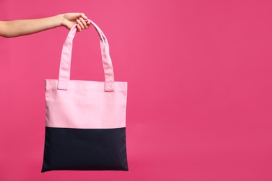 Young woman holding textile bag on pink background, closeup