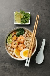 Delicious ramen with shrimps and egg in bowl served on grey table, flat lay. Noodle soup