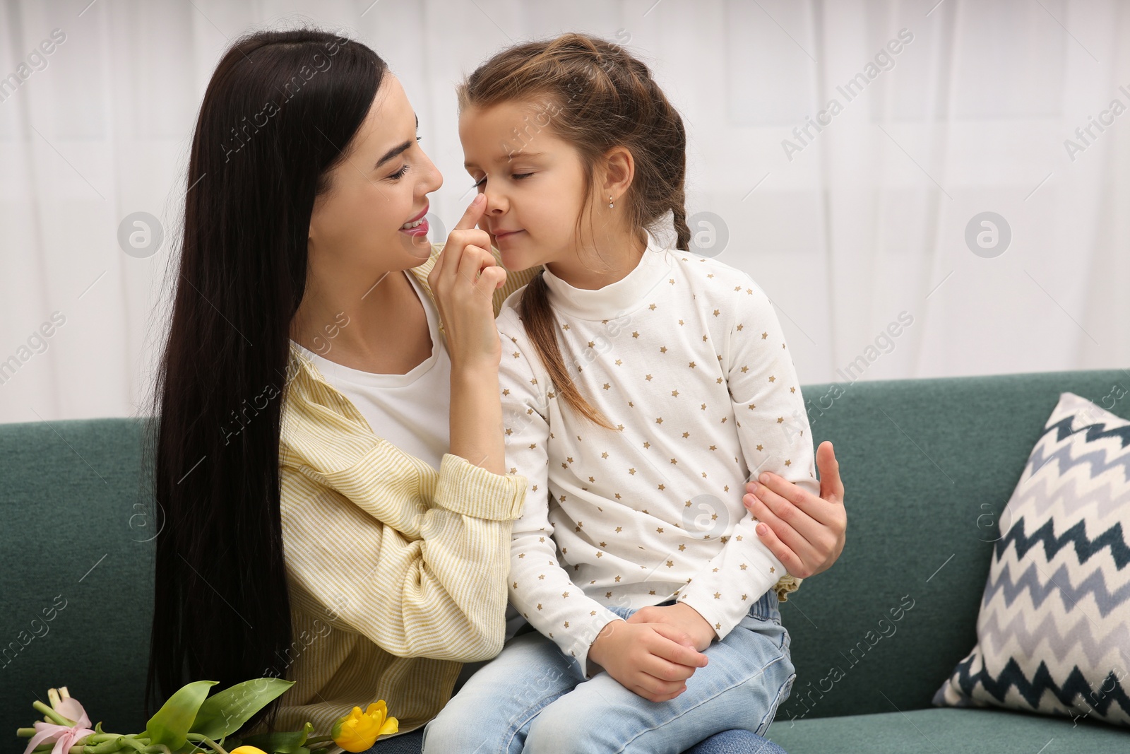 Photo of Happy woman with her daughter on sofa at home. Mother's day celebration