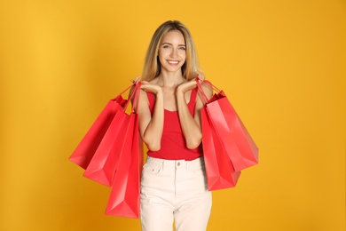 Happy young woman with shopping bags on yellow background. Black Friday Sale