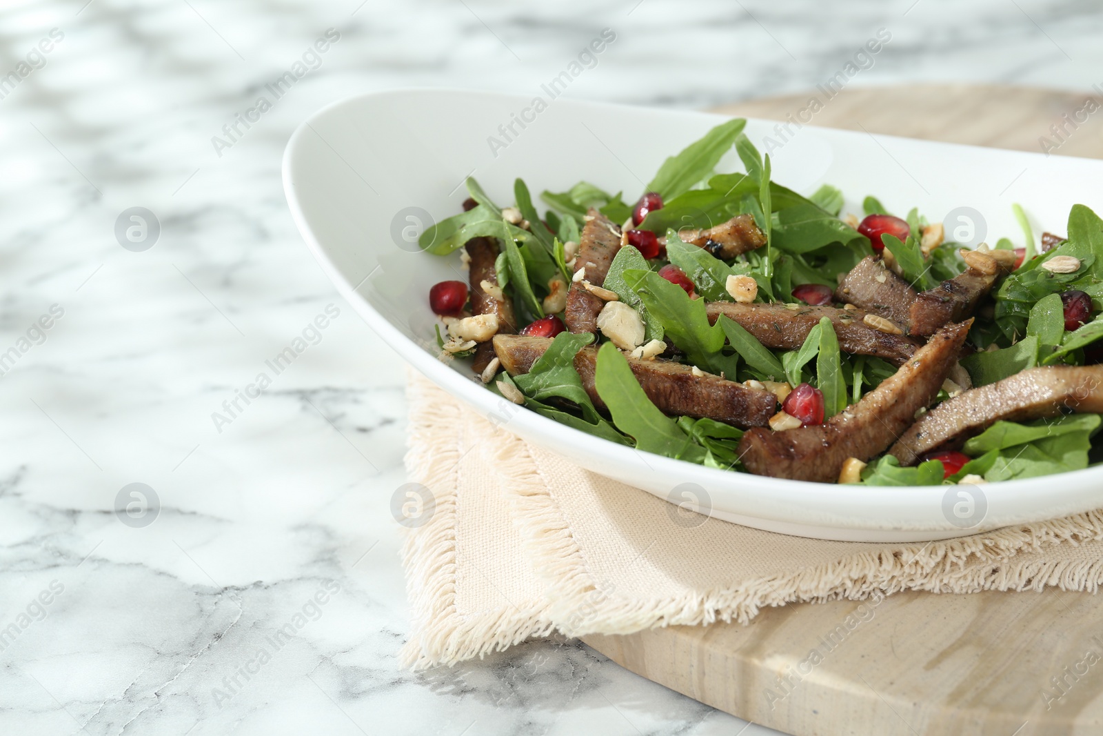 Photo of Delicious salad with beef tongue, arugula and seeds on white marble table. Space for text