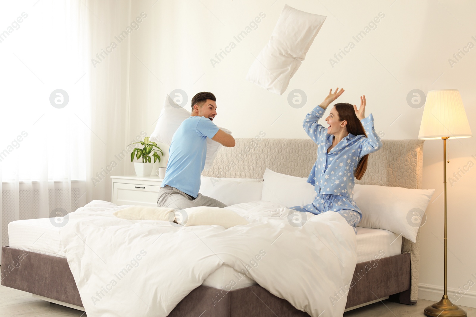 Photo of Happy couple having pillow fight in bedroom