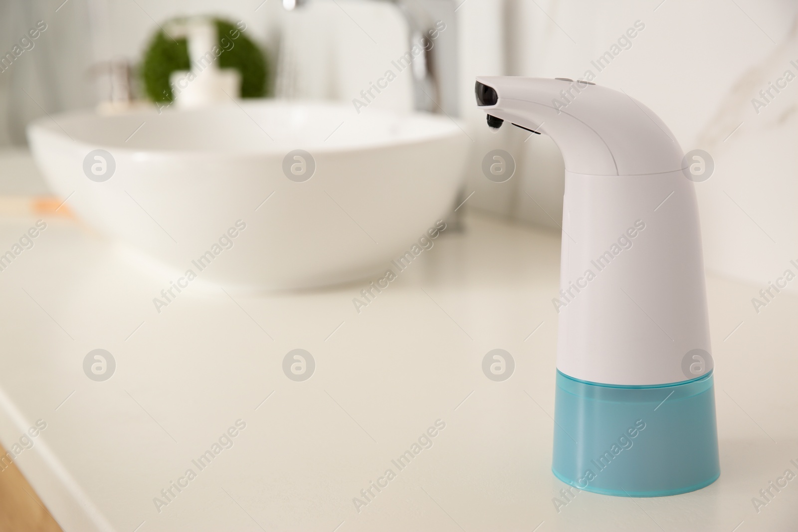 Photo of Modern automatic soap dispenser on countertop in bathroom. Space for text