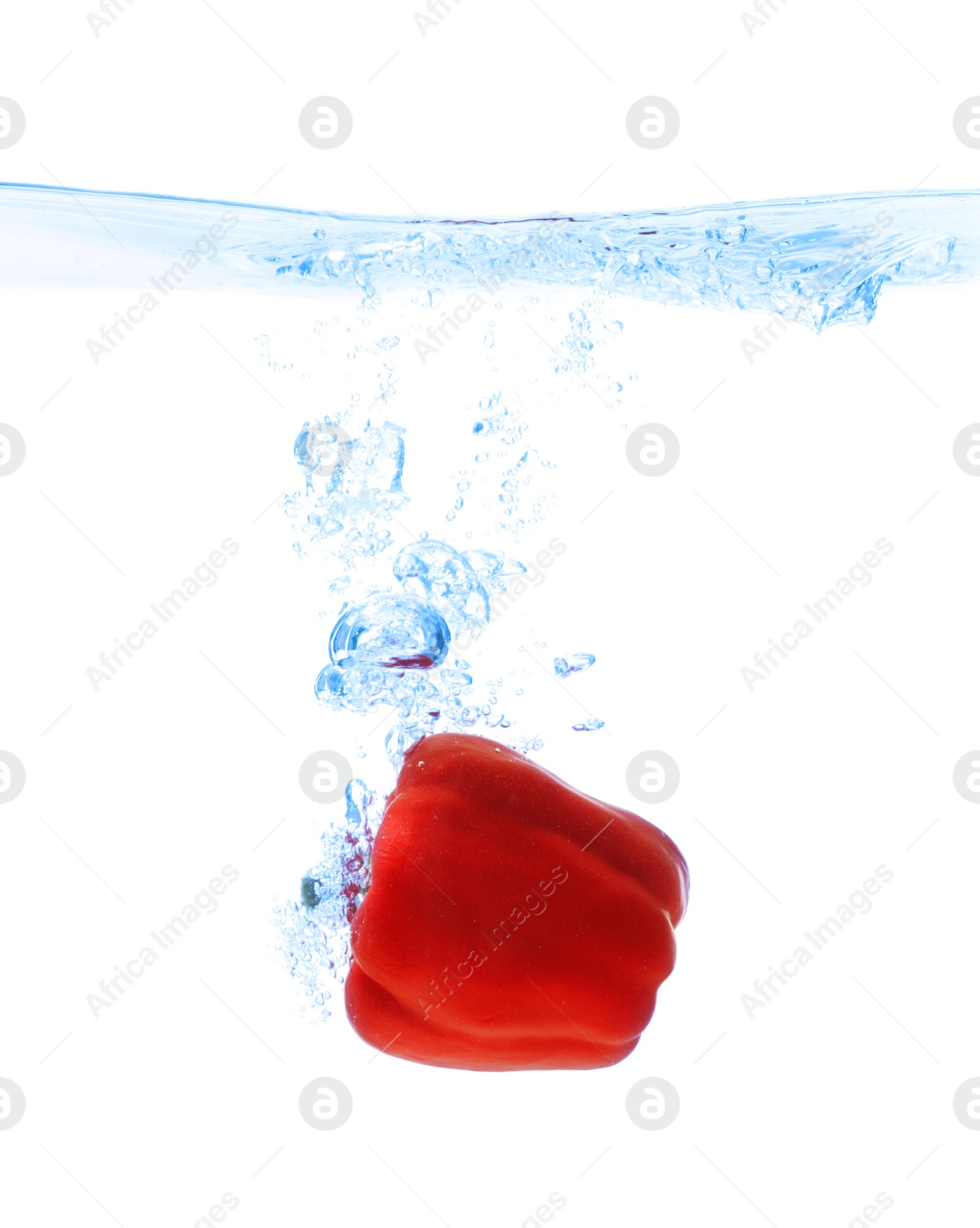 Photo of Red bell pepper falling down into clear water against white background