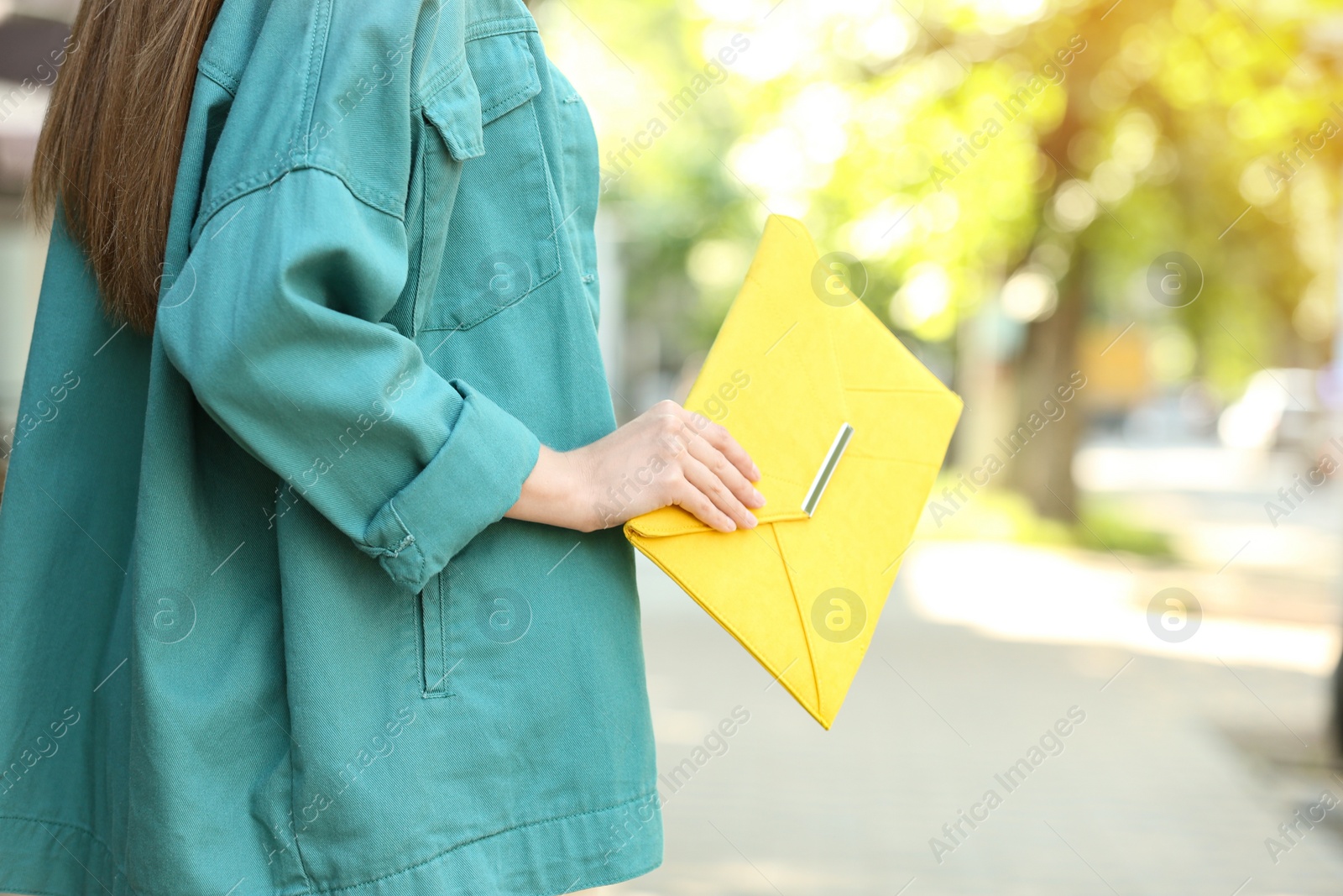 Photo of Young woman with elegant envelope bag outdoors on summer day, closeup