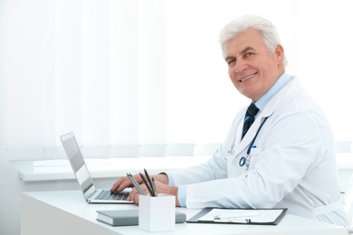 Portrait of senior doctor in white coat at workplace