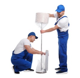 Workers wrapping lamp in stretch film on white background