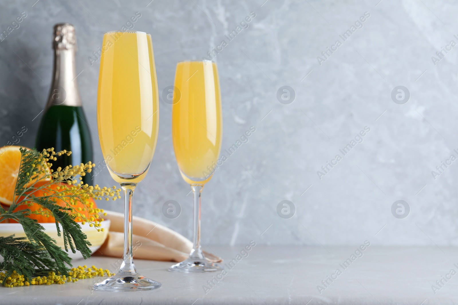 Photo of Glasses of Mimosa cocktail on light table. Space for text