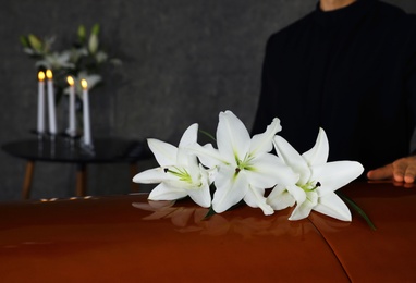 Young man near casket with white lilies in funeral home