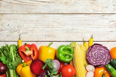 Photo of Flat lay composition with assortment of fresh vegetables on wooden background. Space for text