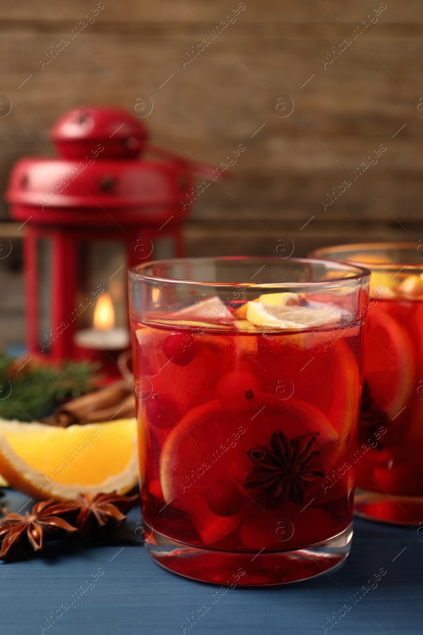 Photo of Delicious punch drink with cranberries and orange on blue wooden table