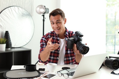 Photo of Portrait of photo blogger with camera and laptop at home. Online broadcast