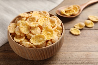 Photo of Bowl and spoon with tasty corn flakes on wooden table, closeup