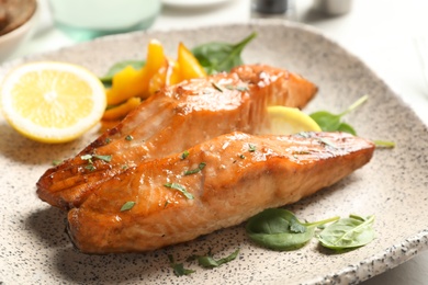 Tasty cooked salmon with lemon on plate, closeup