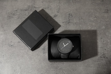 Photo of Box with stylish wrist watch on gray background, top view. Fashion accessory
