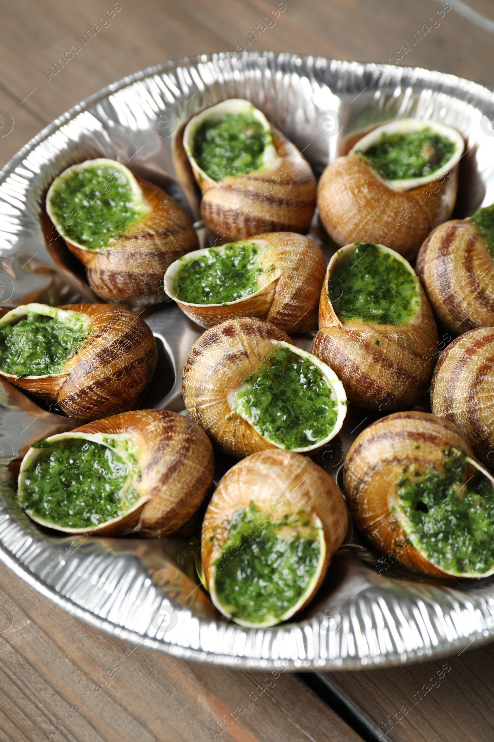 Photo of Delicious cooked snails on wooden table, closeup