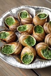 Delicious cooked snails on wooden table, closeup