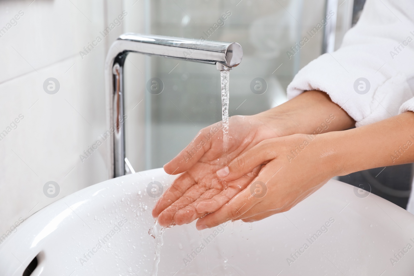 Photo of Woman washing hands over sink in bathroom, closeup. Using soap