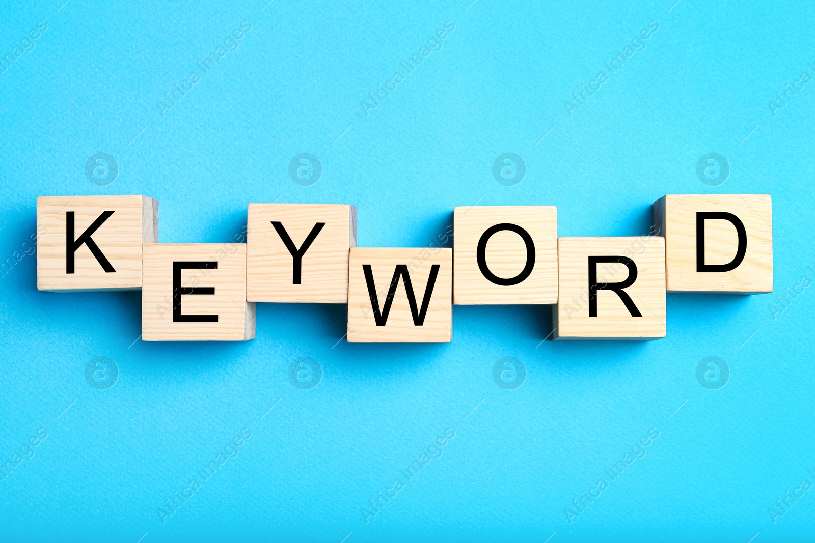 Photo of Wooden cubes with word KEYWORD on light blue  background, flat lay