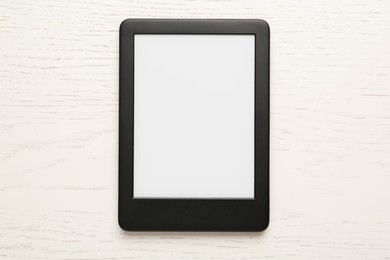 Photo of Modern e-book reader with blank screen on white wooden table, top view