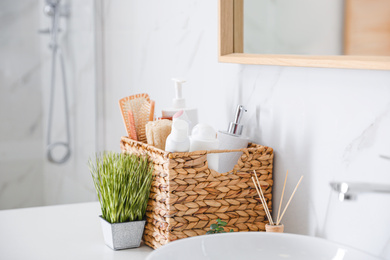 Photo of Different toiletries and green plants on countertop in bathroom