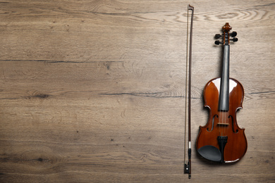 Photo of Classic violin and bow on wooden background, flat lay. Space for text