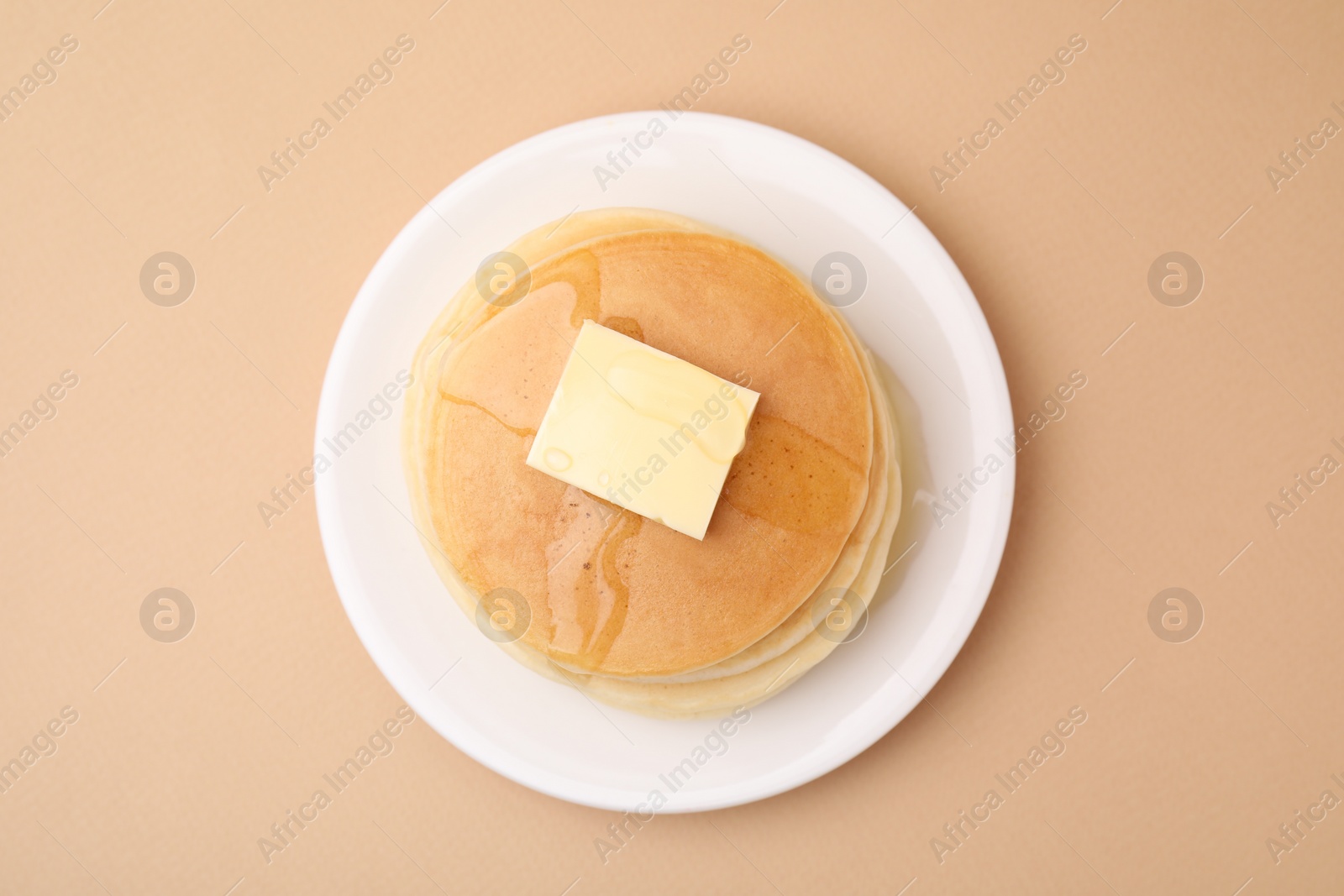 Photo of Delicious pancakes with butter and honey on beige background, top view