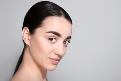 Beautiful woman with perfect eyebrows on light background