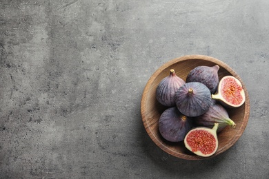 Photo of Bowl with fresh ripe figs on gray background, top view. Space for text