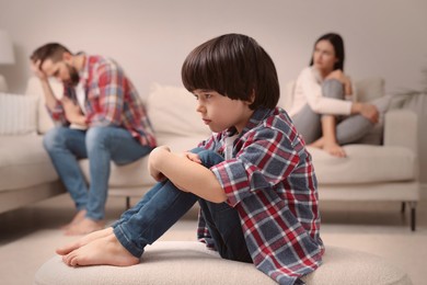 Photo of Sad little boy and his arguing parents on sofa in living room