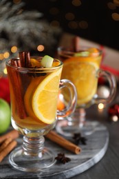 Photo of Aromatic white mulled wine on board against blurred lights