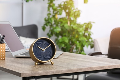 Workplace with stylish analog clock and laptop in office. Space for text