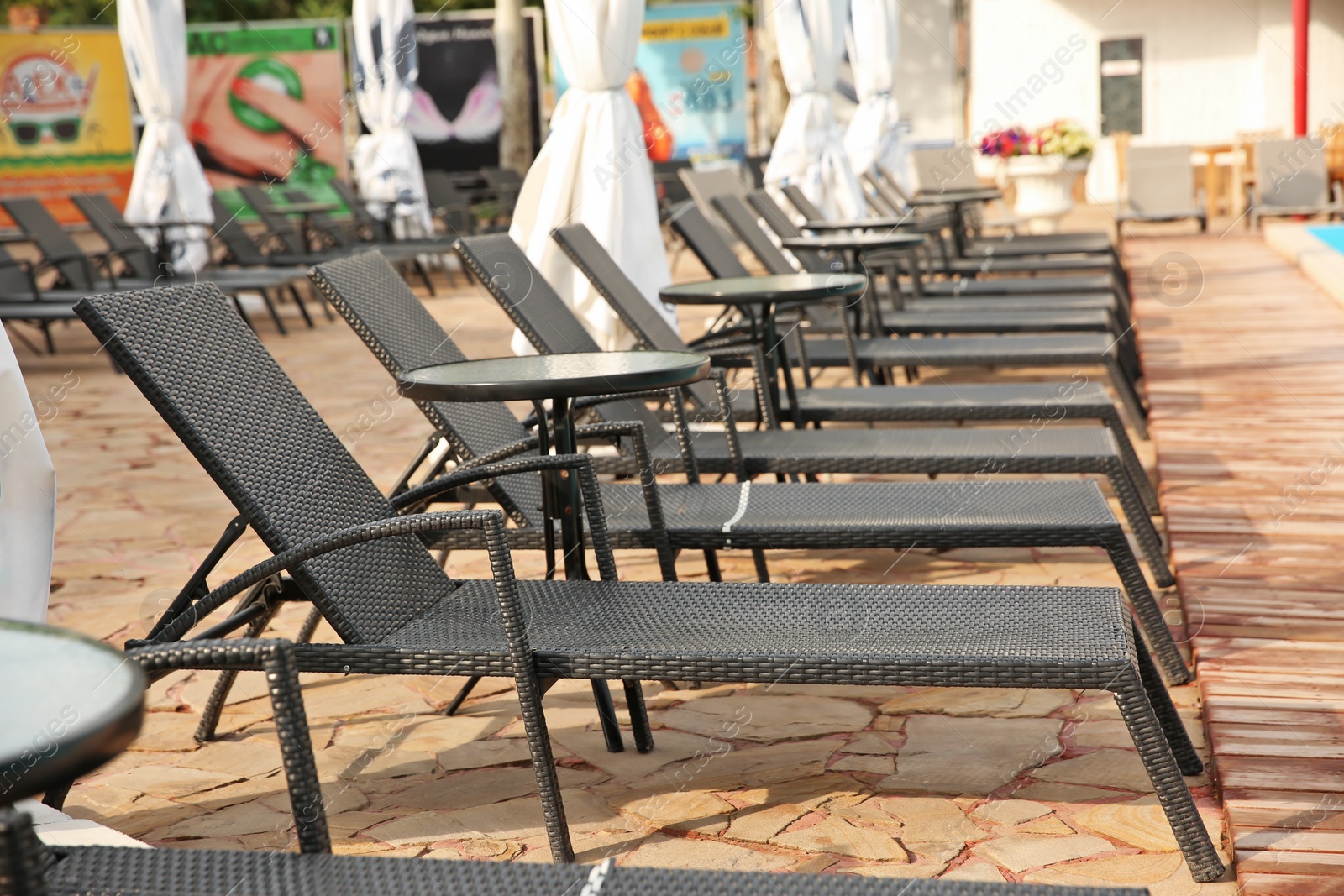 Photo of Sunbeds near modern swimming pool, outdoors