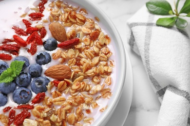 Photo of Smoothie bowl with goji berries on marble table, closeup