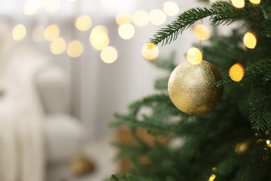 Christmas ball hanging on fir tree branch indoors, closeup. Space for text