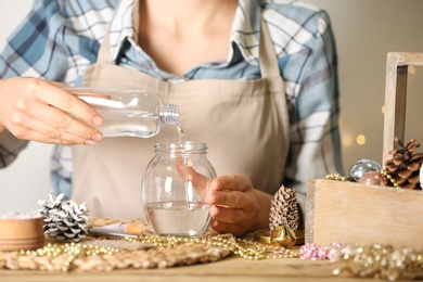 Woman making snow globe at wooden table, closeup