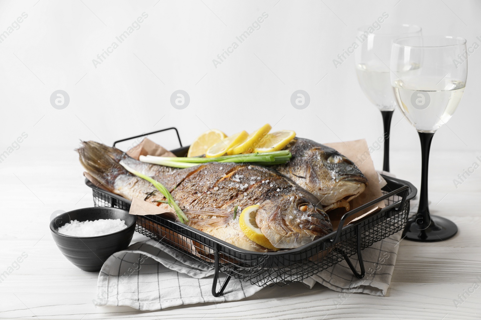 Photo of Seafood. Delicious baked fish served on white wooden table, space for text