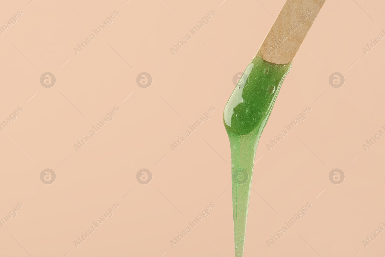 Photo of Wooden spatula with hot depilatory wax on beige background. Space for text