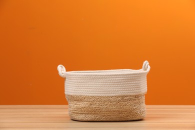 Photo of Empty wicker laundry basket near orange wall