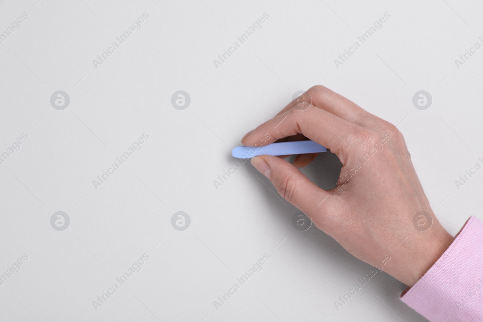 Photo of Woman drawing on white paper with pastel, top view. Space for text