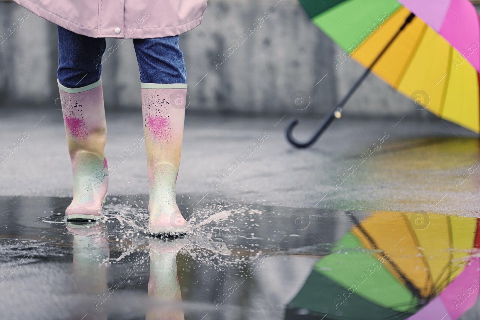 Photo of Woman in rubber boots walking outdoors on rainy day, closeup