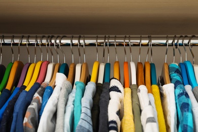 Photo of Hangers with teenage clothes on rack in wardrobe, closeup