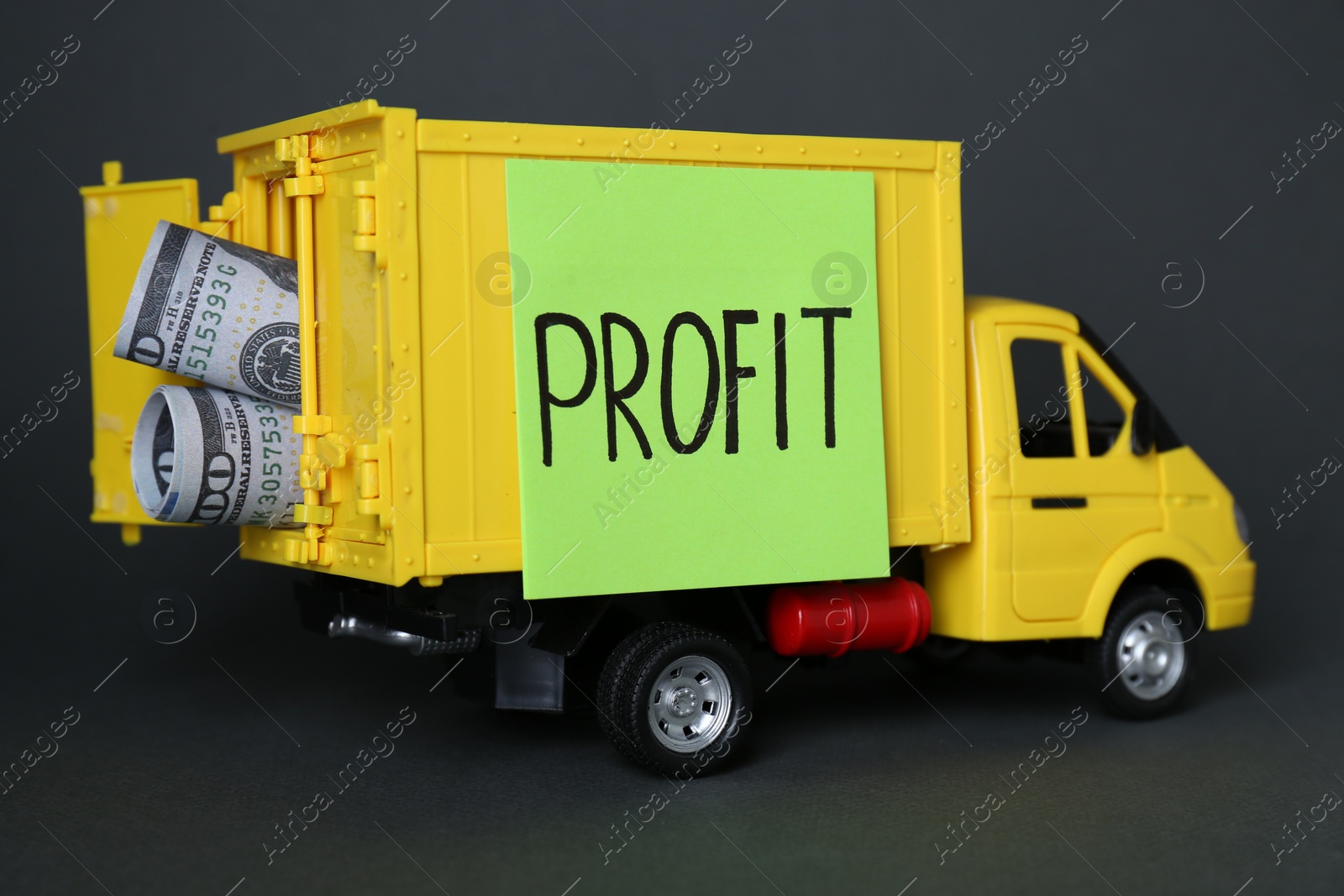 Photo of Economic profit concept. Toy truck with banknotes on black background