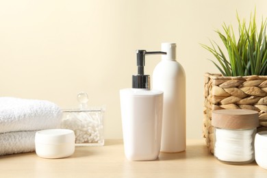 Photo of Different bath accessories and houseplant on wooden table against beige background, closeup