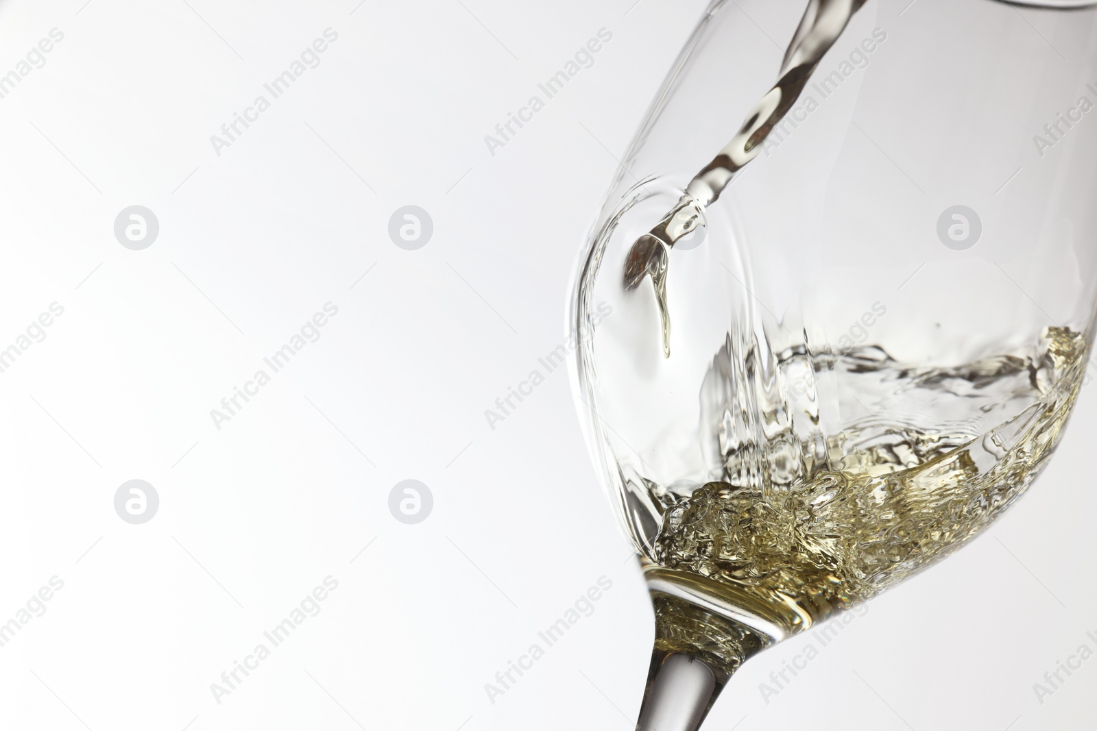 Photo of Pouring tasty aromatic wine in glass on white background, closeup. Space for text